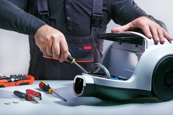 Repairman repairing of vacuum cleaner.