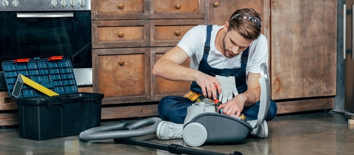 professional repairman fixing vacuum cleaner