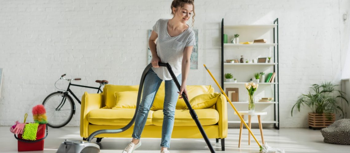 happy girl cleaning carpet with vacuum cleaner